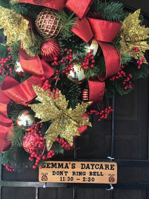 The front door of Gemma's Daycare, dressed with a holiday wreath and a hand-made wooden sign